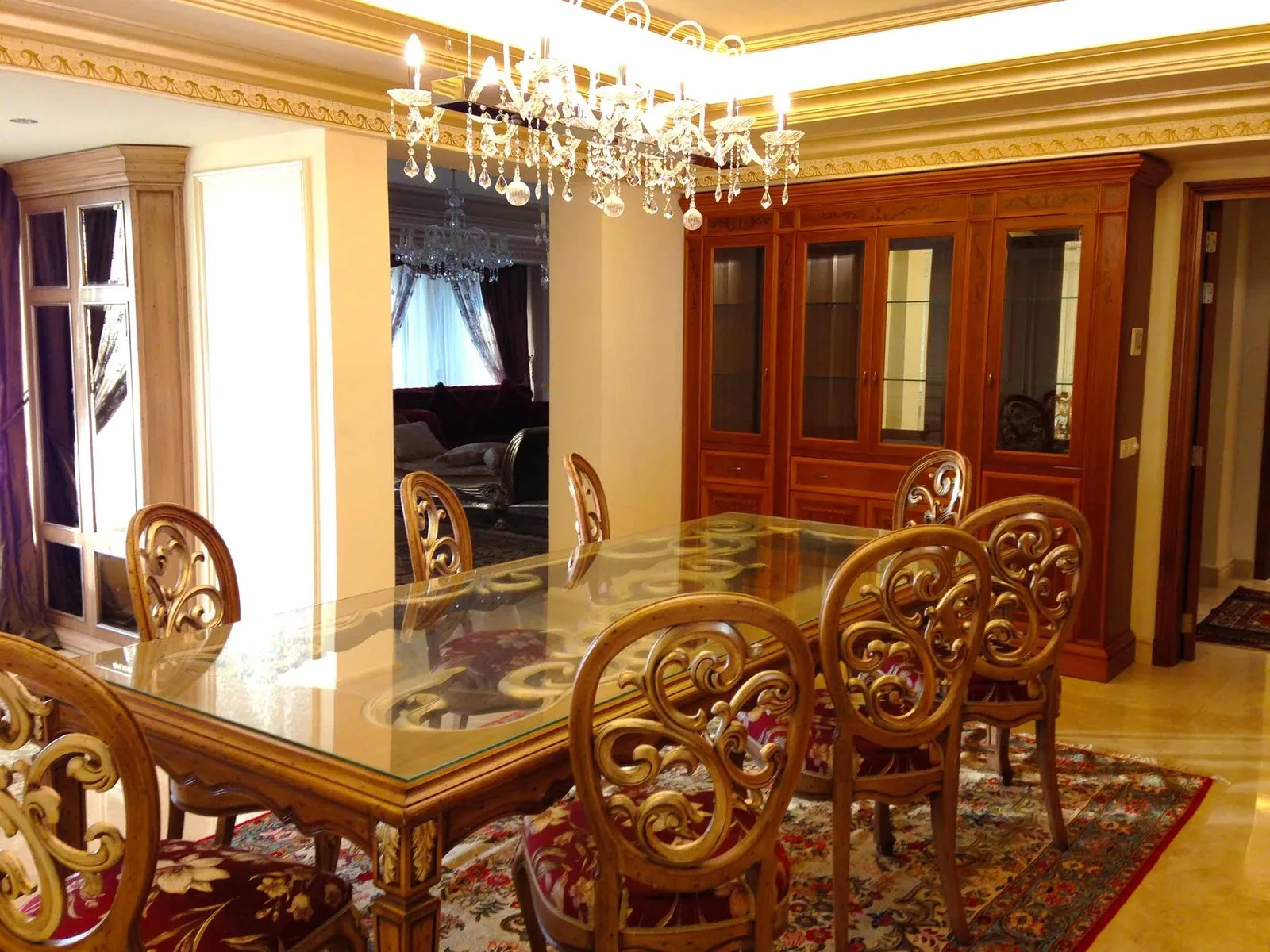 Dining room in a Beirut residence with carved timber chairs, a glass-topped table and a crystal chandelier