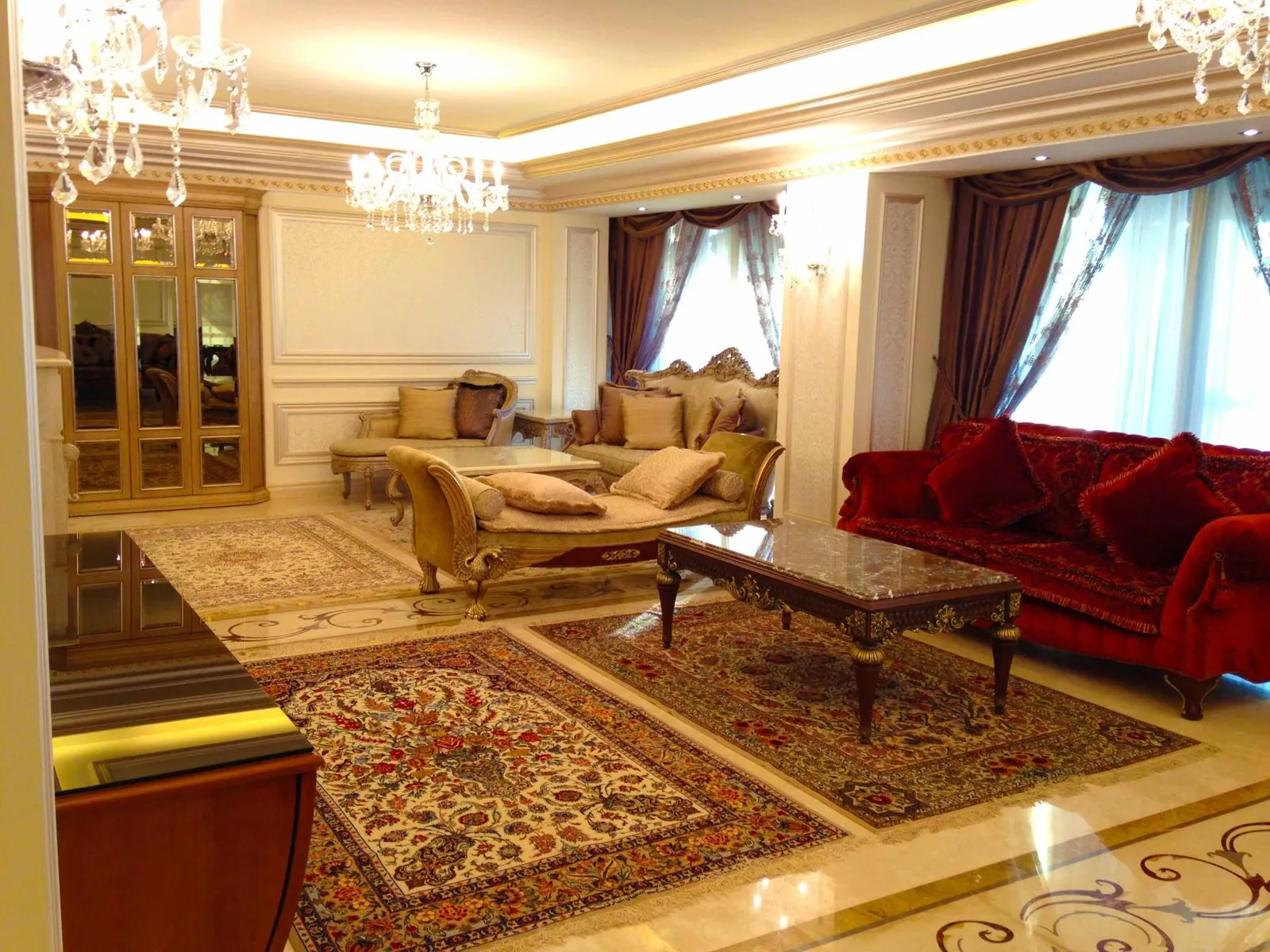 Formal reception room in a Beirut residence — mirrored cabinetry, crystal chandeliers, patterned marble flooring and layered rugs